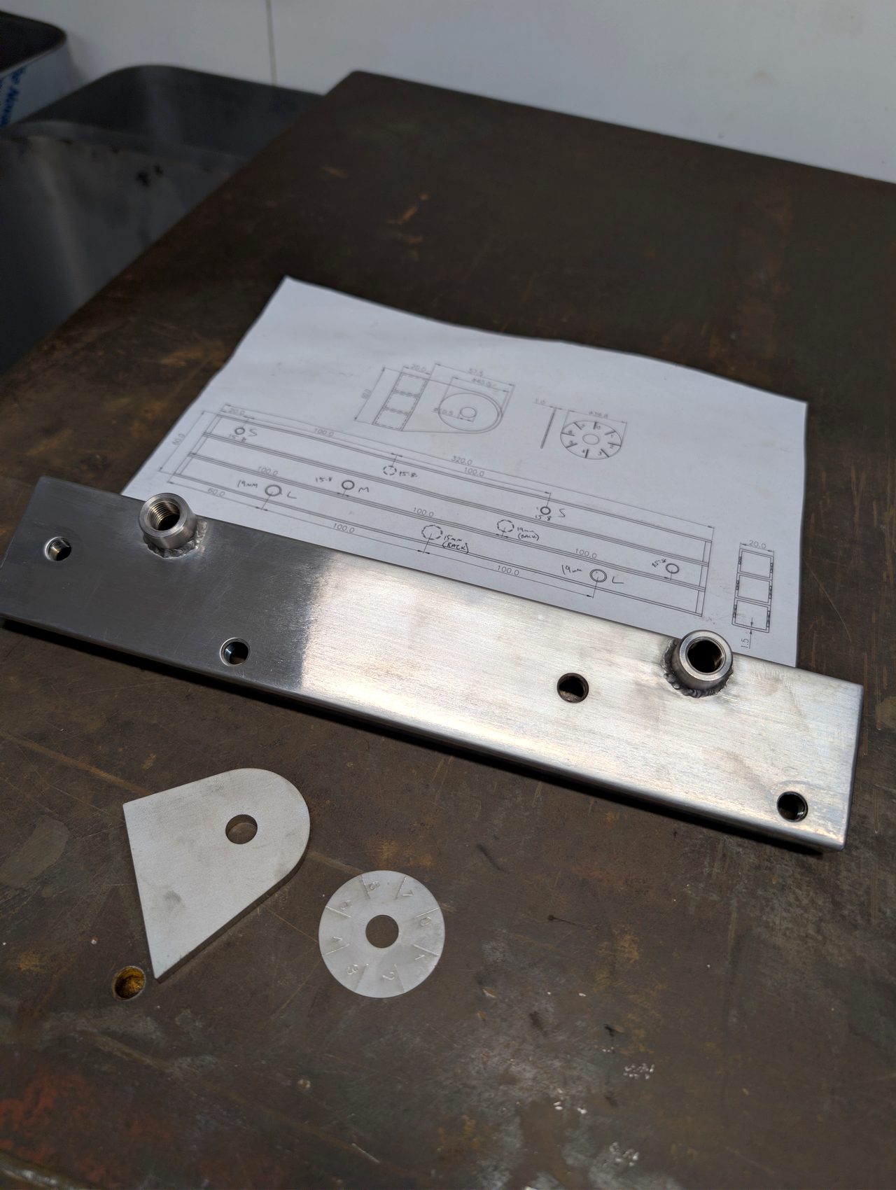 Fabricated parts laid out beside an engineering drawing
